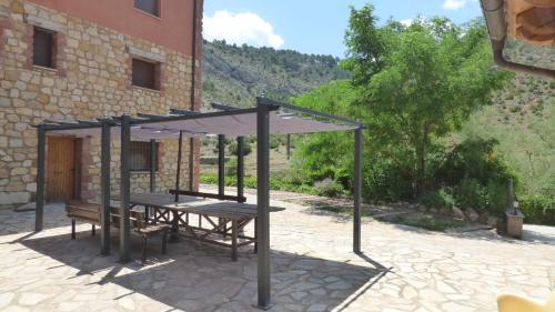 a picnic table with a canopy in front of a building at Las Aliagas Apartamentos Rurales in Megina