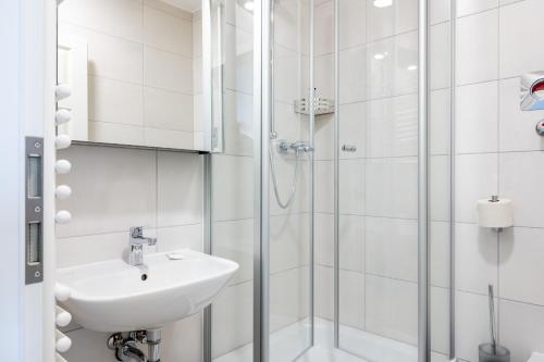 uma casa de banho branca com um lavatório e um chuveiro em JOHOUSE Apartment 7 em Warnemünde