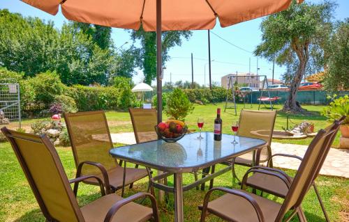 un tavolo e sedie sotto un ombrellone in un cortile di Noufris House Roda Corfu a Roda