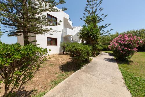 a white house with trees and flowers on a sidewalk at Ohana in Kamisianá