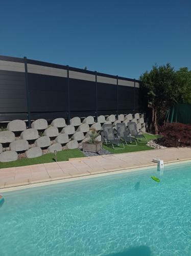 une piscine avec des chaises blanches et une clôture dans l'établissement Happy Plaine, à Sainte-Croix-en-Plaine