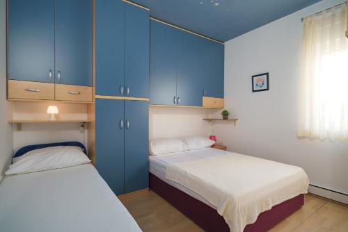 two beds in a room with blue cabinets at Apartmani NEDOKLAN in Srima