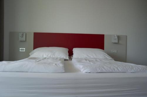 2 letti con lenzuola bianche e una parete rossa di Agriturismo Le Campagnole a Bardolino