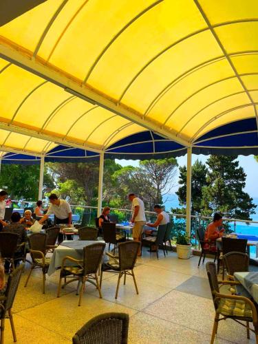 a group of people sitting at tables under a yellow umbrella at CORPUS B - Hotel Albatros in Ulcinj