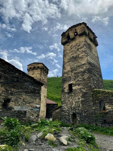 an old stone building with two towers on a hill at Nizharadze's Tower in Ushguli