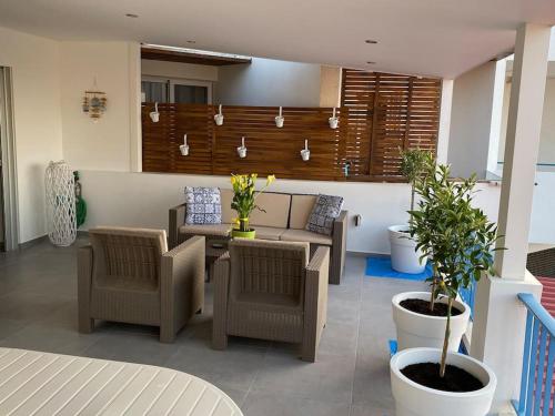 een woonkamer met stoelen, een bank en planten bij Casa Azzuro - Luxurious Modern Apartment Kapparis in Paralimni