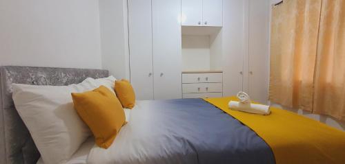 1 dormitorio con 1 cama con almohadas amarillas y blancas en Marahomes, en Bushey
