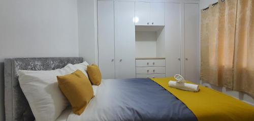 a bedroom with a bed with yellow and white pillows at Marahomes in Bushey