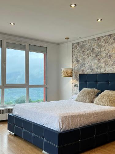 a large blue bed in a bedroom with windows at Oviedo Real Spa in Oviedo