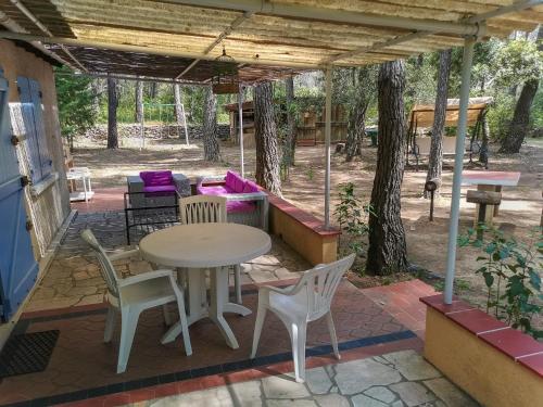 un patio avec une table et des chaises sous une pergola dans l'établissement Maisonnette en pleine nature, au Beausset