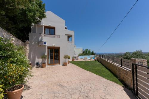 a white house with a fence and a walkway at Linari Villa, a peaceful & cozy 2bdr villa with private pool! in Agia Triada