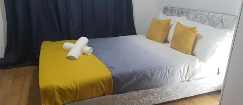 a bed with yellow and white sheets and pillows at Marahomes in Bushey