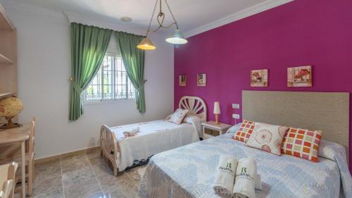 - une chambre avec 2 lits et des murs violets dans l'établissement Casa Los Lirios Antequera - La Higuera by Ruralidays, à Antequera