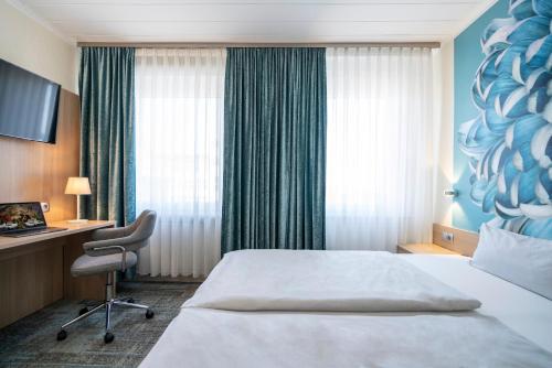 a hotel room with a bed and a desk at NP Hotel Königshof in Dortmund
