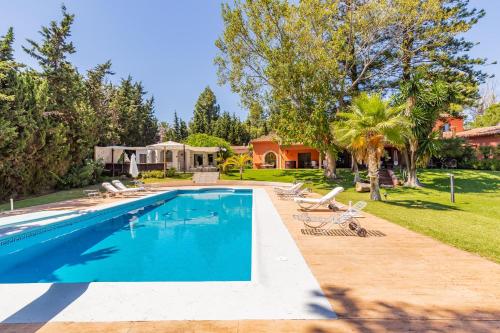una piscina con sillas y una casa en Villa Hacienda del Mar, en Marbella