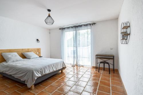 a bedroom with a bed and a table on a tiled floor at Villa Signo - Piscine privée in Signes