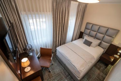 a bedroom with a bed and a desk and a television at NP Hotel Königshof in Dortmund