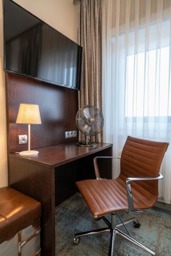a room with a desk with a chair and a lamp at NP Hotel Königshof in Dortmund
