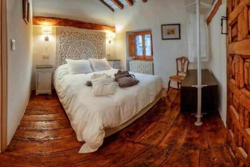 a bedroom with a large white bed with wooden floors at Casa Rural La Chascona in Pedrajas