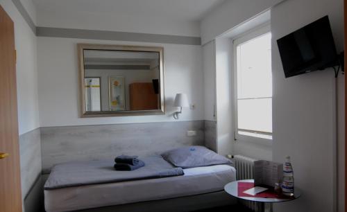 a bedroom with a bed and a mirror and a table at Nell-Breuning-Hotel in Herzogenrath