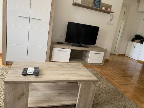 a living room with a tv and a wooden table at Apartmani CENTAR Vrnjacka Banja & Free Parking in Vrnjačka Banja