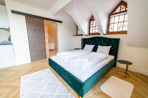 a bedroom with a large bed with a green headboard at Apartamenty Mazurskie in Mikołajki