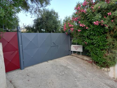 a blue gate with a bush with pink flowers at Paleokastritsa Red Gate Flat in Paleokastritsa