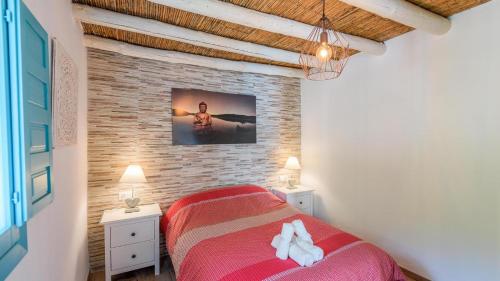 a bedroom with a red bed and a brick wall at Casa La Higuera Competa by Ruralidays in Frigiliana