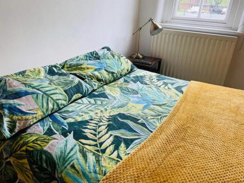 a bed with a colorful blanket on it with a lamp at 2 Bed Self Contained Apartment Wrexham in Wrexham