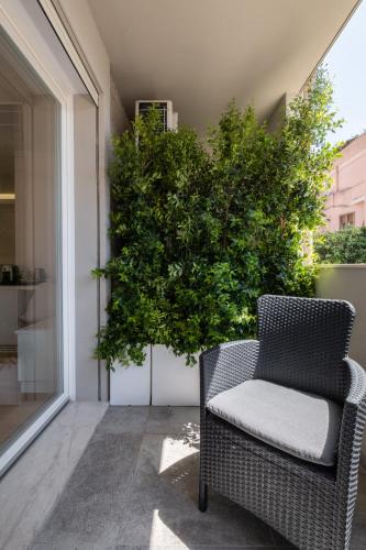a wicker chair sitting on a balcony with a large plant at Helios Guest House in Cagliari