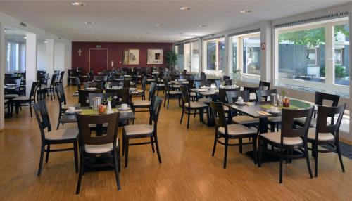 uma sala de jantar com mesas, cadeiras e janelas em Nell-Breuning-Hotel em Herzogenrath