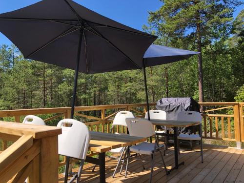 a table and chairs with an umbrella on a deck at Timber cottages with jacuzzi and sauna near lake Vänern in Karlstad