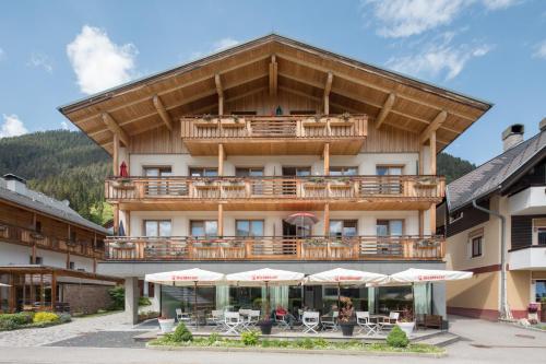 a hotel with a balcony with tables and umbrellas at Draxl-Hof Ferienwohnungen in Weissensee