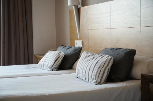 a bedroom with a bed with two pillows on it at Ohtels Campo De Gibraltar in La Línea de la Concepción