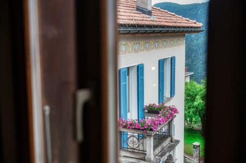 a window view of a building with blue shutters and flowers at Casa Bella Oschesina by Quokka 360 - in the village of Osco in Osco