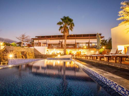 a house with a swimming pool in front of a building at King Fisher Village in Tarrafal