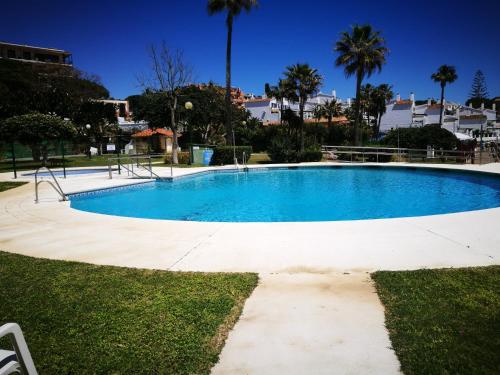 a blue swimming pool with palm trees in the background at BEACH ALMIRANTE 9 MIJAS Marbella in Sitio de Calahonda