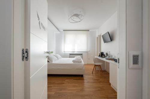 a white bedroom with a bed and a desk at Helios Guest House in Cagliari