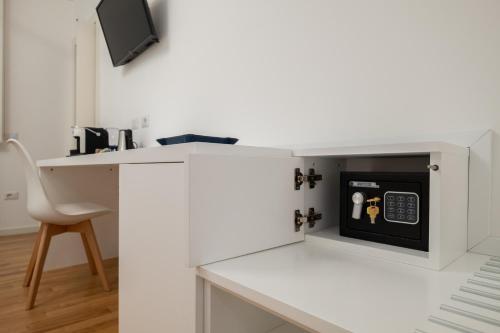 a white kitchen with a desk and a microwave at Helios Guest House in Cagliari
