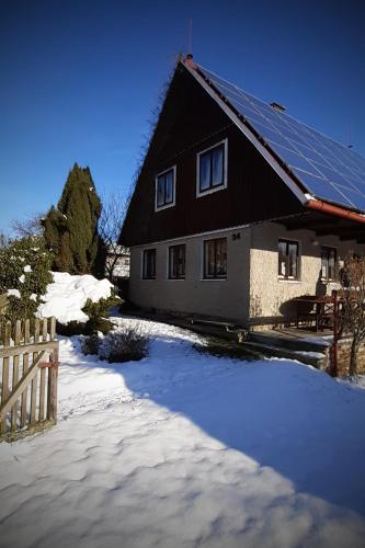 a house with solar panels on the roof in the snow at Chalupa Vršovka in Vršovka