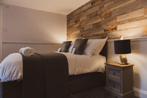 1 dormitorio con 1 cama con pared de madera en The Stag Hotel, Restaurant and Bar en Lyndhurst