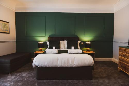 a bedroom with a large bed and a green wall at The Stag Hotel in Lyndhurst