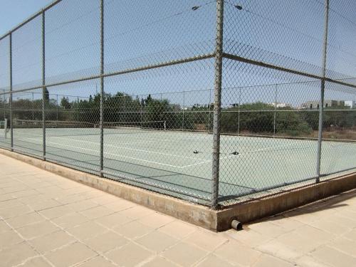 Attraverso una recinzione si intravedono due campi da tennis. di Panorama Village Complex a Paralimni