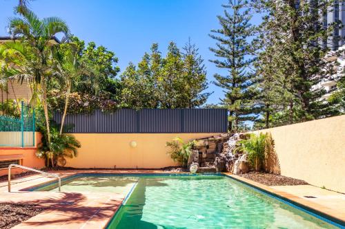 a swimming pool in front of a building with trees at Aruba Sands Resort in Gold Coast