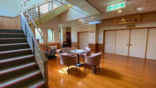 an office with a staircase and a table and chairs at Tabinoyado Yakurai Rinsenkan in Osaki