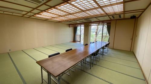 a large room with a long table and chairs at Tabinoyado Yakurai Rinsenkan in Osaki