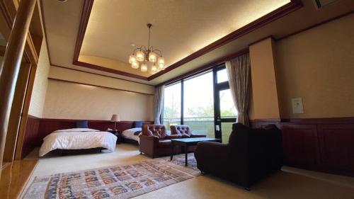 a bedroom with a bed and a couch and a chair at Tabinoyado Yakurai Rinsenkan in Osaki