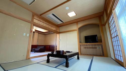 a living room with a table and a tv at Tabinoyado Yakurai Rinsenkan in Osaki