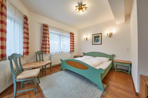 a bedroom with a green bed and a table and chairs at Chalet Haider in Saalbach Hinterglemm