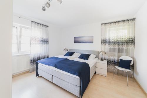 um quarto branco com uma cama azul e uma cadeira em Ferienwohnung im Fischerhaus em Nonnenhorn